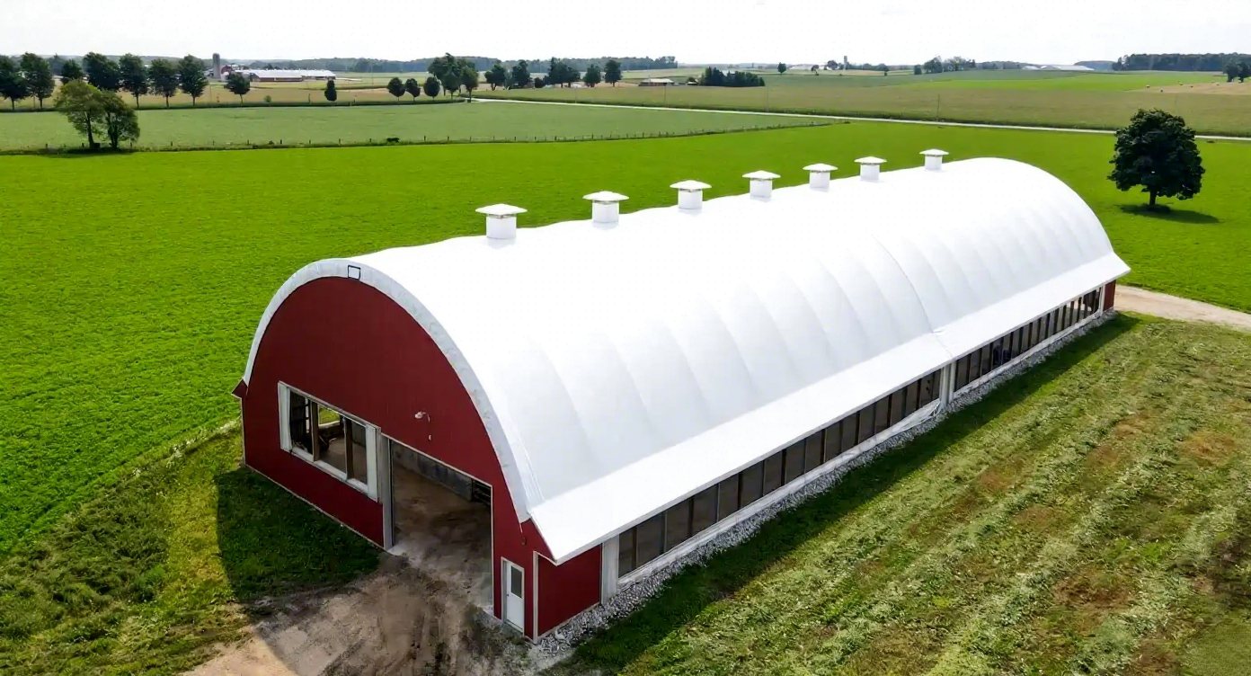 Red dairy barn aerial in green fields